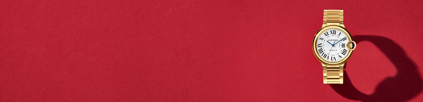 Montre Ballon Bleu de Cartier en or jaune sur un fond rouge.